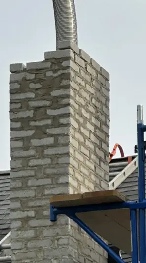 A brick chimney with a corrugated hose running into the flue during a cleaning.